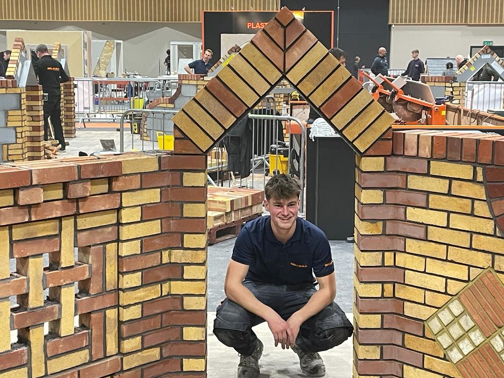 Joe Shinger crouching beneath brick archway