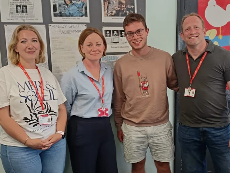 Student standing next to three members of staff