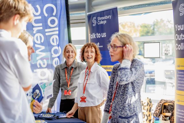 Three smiling members of staff at a student recruitment event