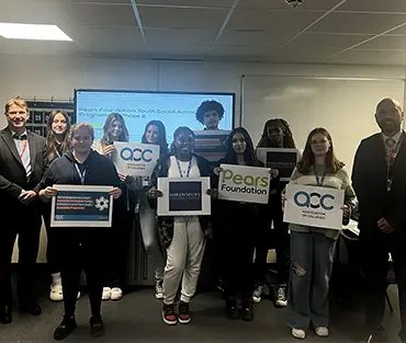 A group of students holding posters next to the college principal