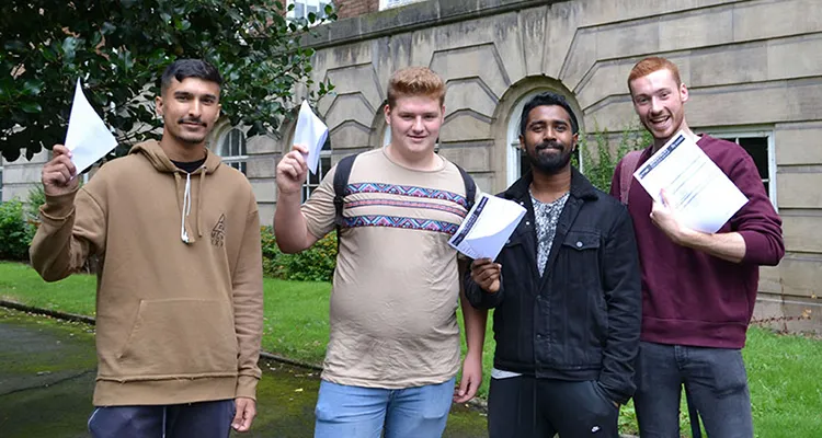 Four students standing in front of college with certificates