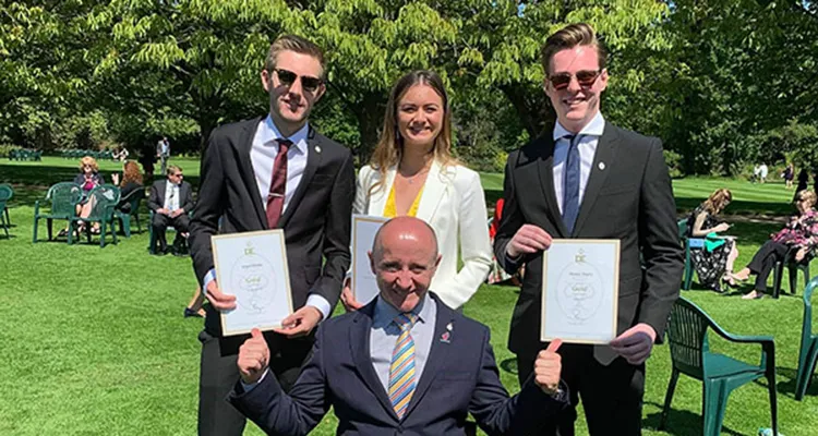 Three students standing behind Paralympian and TV presenter, Sean Rose