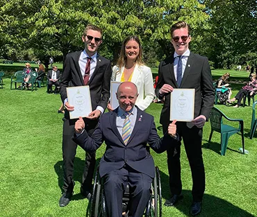 Three students standing behind Paralympian and TV presenter, Sean Rose