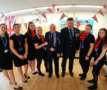 A group of travel and tourism students standing with two veterans