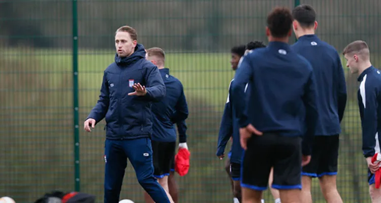 Sports teacher coaching a group of football students