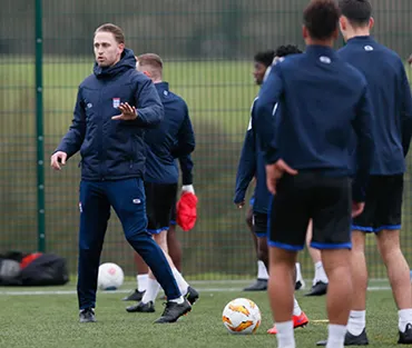 Sports teacher coaching a group of football students