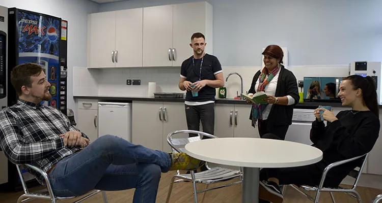 Two male and two female mature students drinking coffee and chatting in the HE Centre’s kitchen