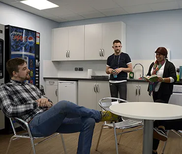 Two male and two female mature students drinking coffee and chatting in the HE Centre’s kitchen