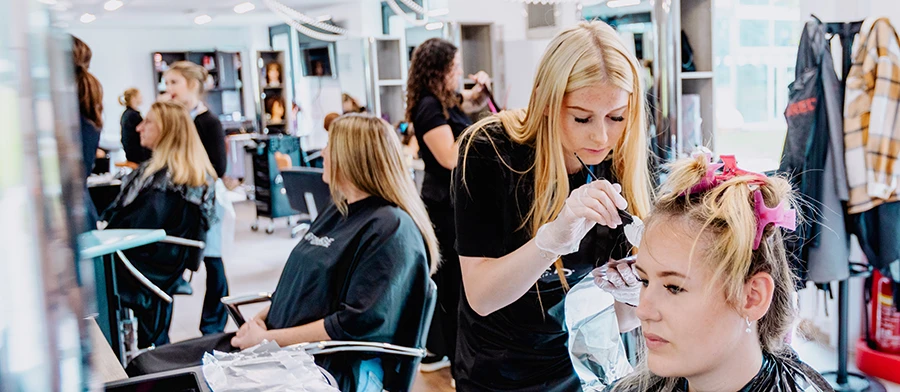 Student applying nail polish to client