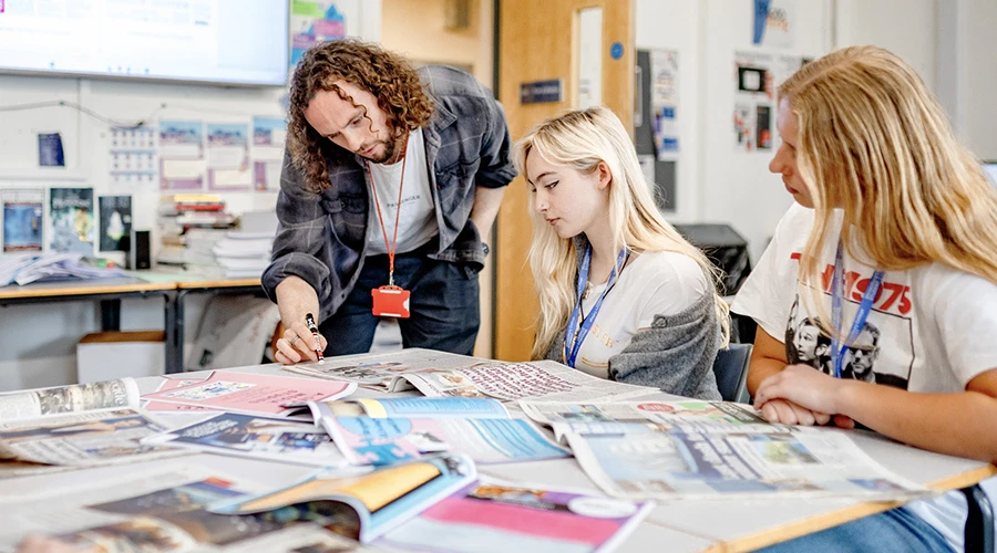 Teacher and students reviewing newspapers
